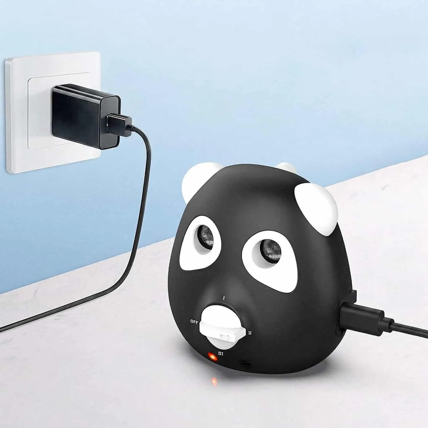 Black and white panda shaped ultrasonic bark deterrent device with dual speakers in the eyes and frequency dial