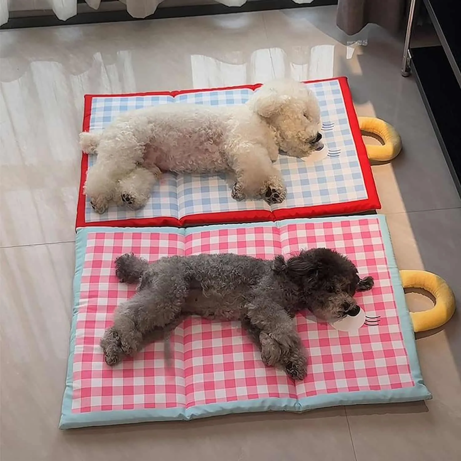Blue plaid ice silk pet cooling pad with red border and waterproof surface shown with a small white dog lying on it
