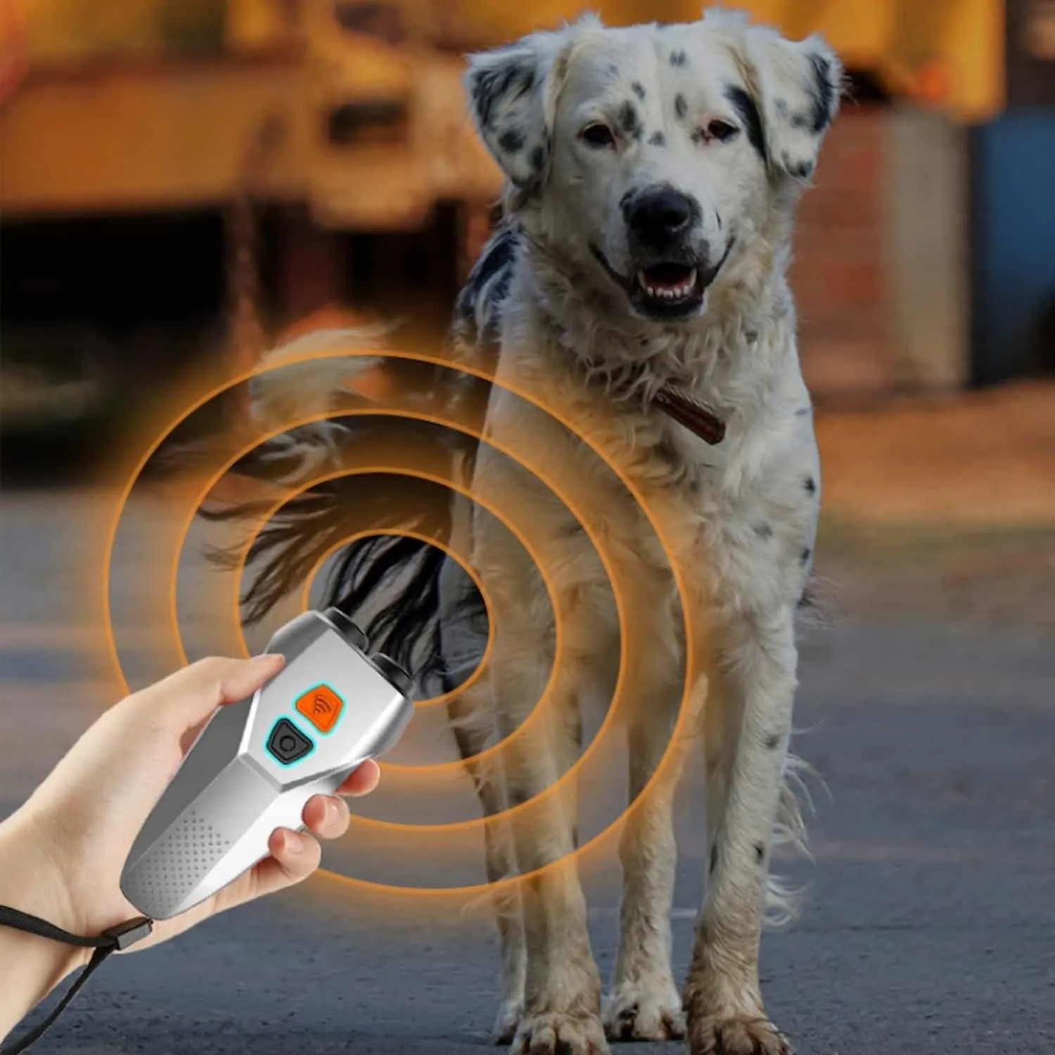 Silver handheld ultrasonic dog bark deterrent with dual speakers, orange training button, blue deterrent button, and wrist strap